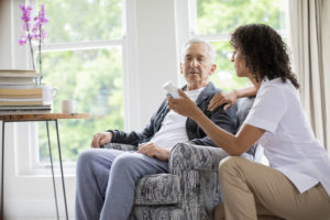 Caregiver showing pill bottle to senior patient