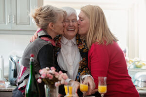 adult daughters kissing senior mother