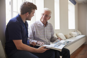 caregiver and senior man looking at photo album