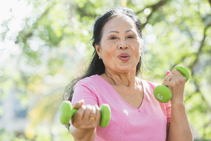 A woman uses hand weights during her exercise routine, one of a number of stroke prevention tips for older adults.