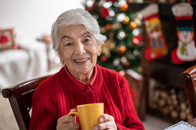 An older woman enjoys tea during the holidays. She now receives home care support thanks to the signs her family noticed when visiting elderly loved ones during the holiday season.